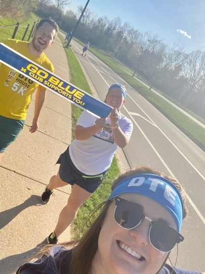 3 people running holding go blue sign